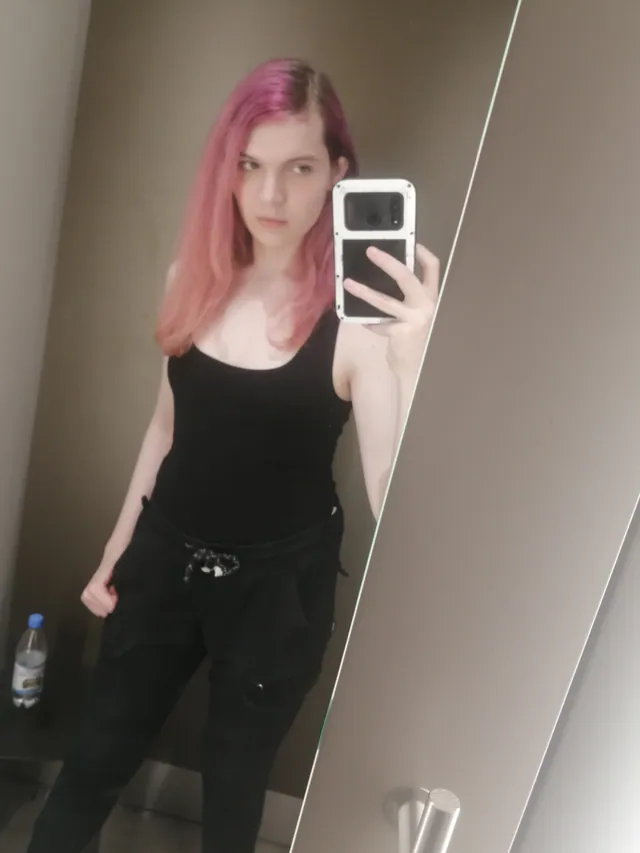 Mirror selfie of Liz in a black tank top and black jeans